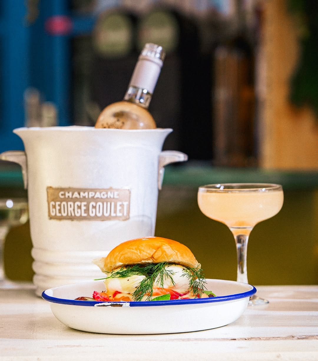 Eggs Benedict with dill beside a chilled bottle of rosé in an ice bucket