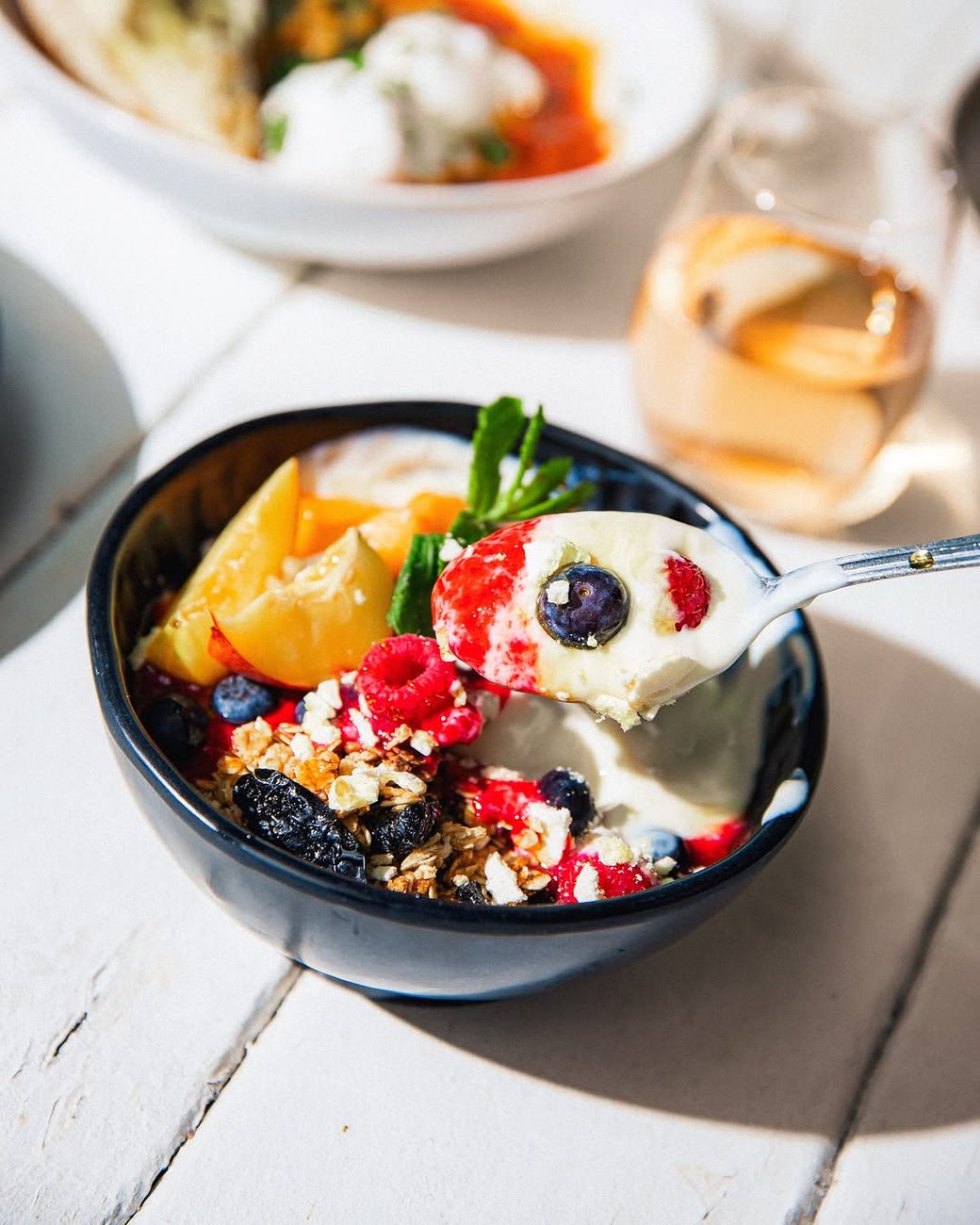 Yoghurt bowl with peach, berries, granola and mint
