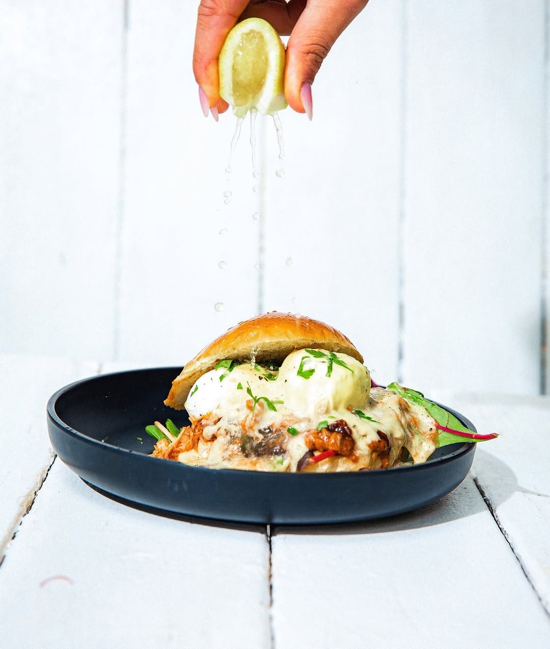 Eggs Benedict with hollandaise and herbs on a dark plate