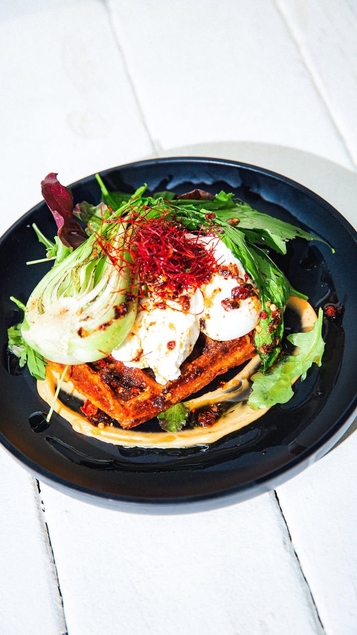 Open toast topped with poached eggs, chilli threads and leaves