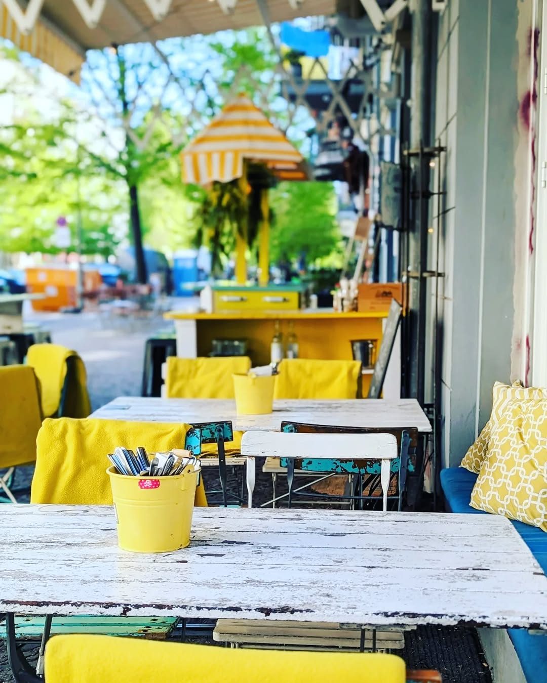 Yellow chairs and tables set up on the terrace under the trees