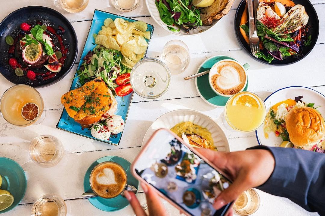 A full brunch table of plates, coffees and glasses seen from above