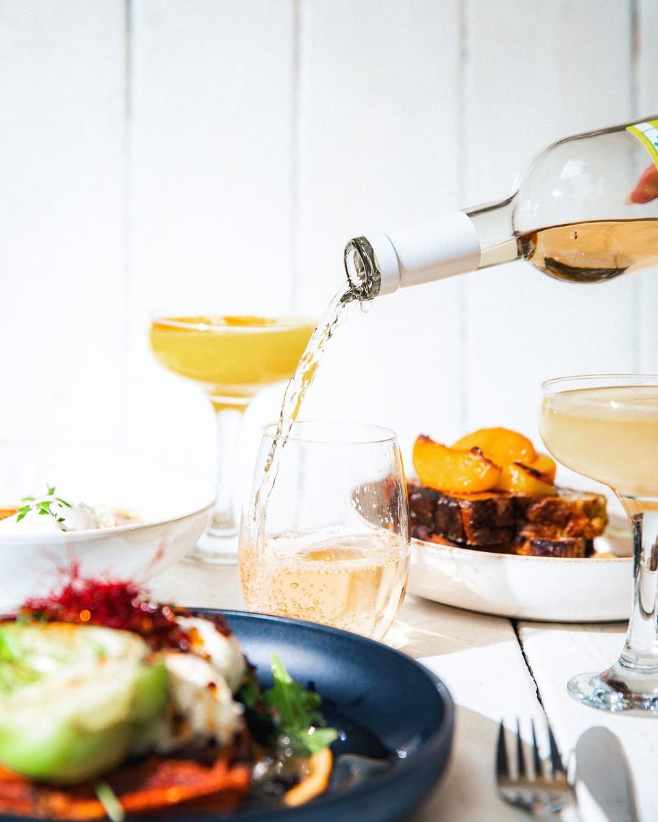A glass being topped up beside plates of brunch