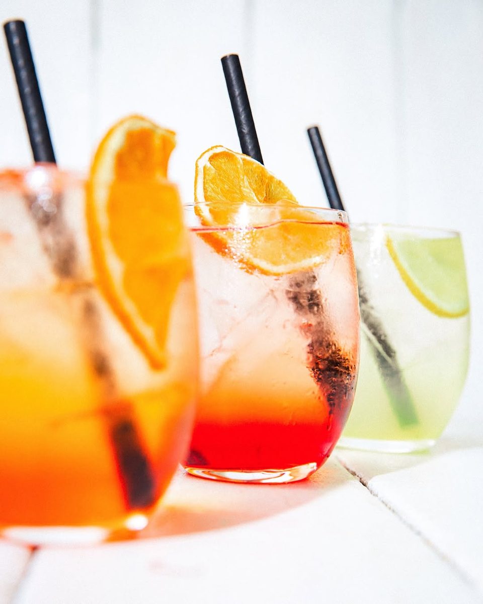 Two orange spritzes with citrus slices on a white table
