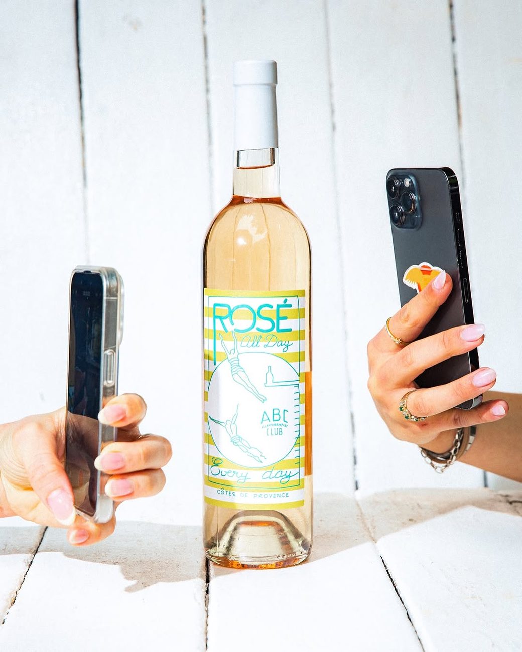 A bottle of ABC Rosé being photographed on a white wooden table